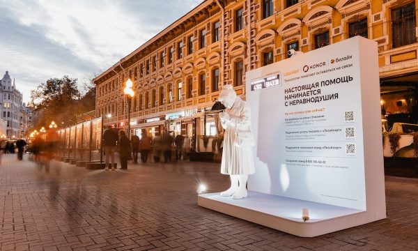 Белая фигура пожилой женщины со смартфоном у стенда на Арбате